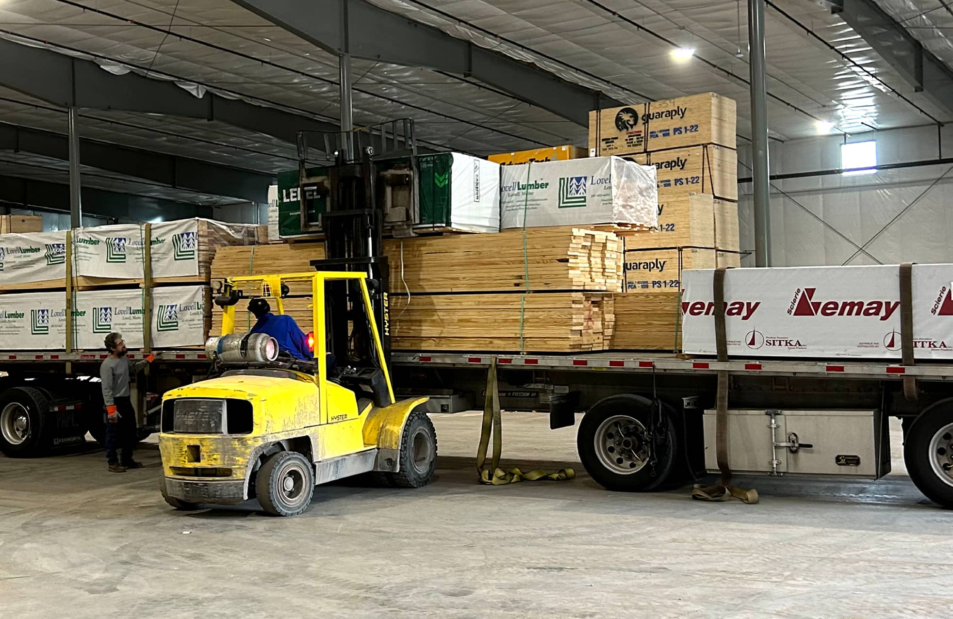 A forklift unloading lumber from a truck